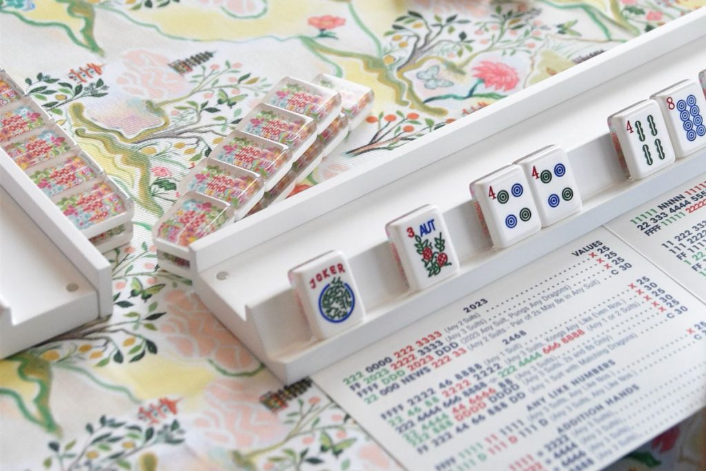 a close up view of beautiful colorful mahjong tiles on a table, with tiles placed on a rack and a mahjong playing card