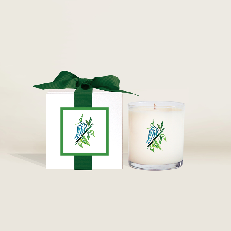 The Ella B. x Mahjong & Magnolias collaboration candle featuring the M&M signature bird bam artwork along with a gift box with green ribbon.