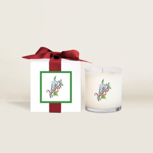 The Ella B. Candles x Mahjong & Magnolias collaboration holiday candle featuring the M&M signature Merry Mahjong holiday bird bam artwork along with a gift box with red ribbon.